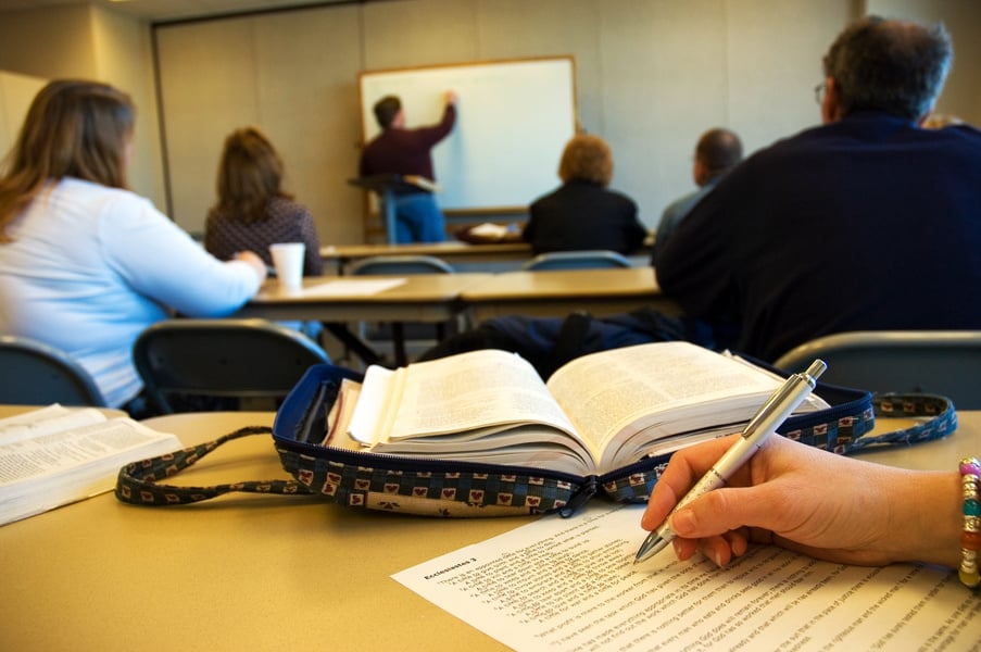 adult bible study class watches the instructor at a whiteboard